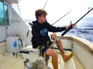 a boy on a boat fishing with a pole